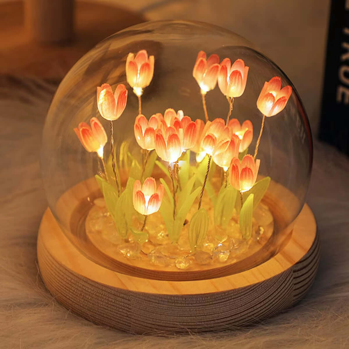 Battery operated tulip night light glowing inside a glass dome on a wooden base, showcasing beautiful LED flowers.